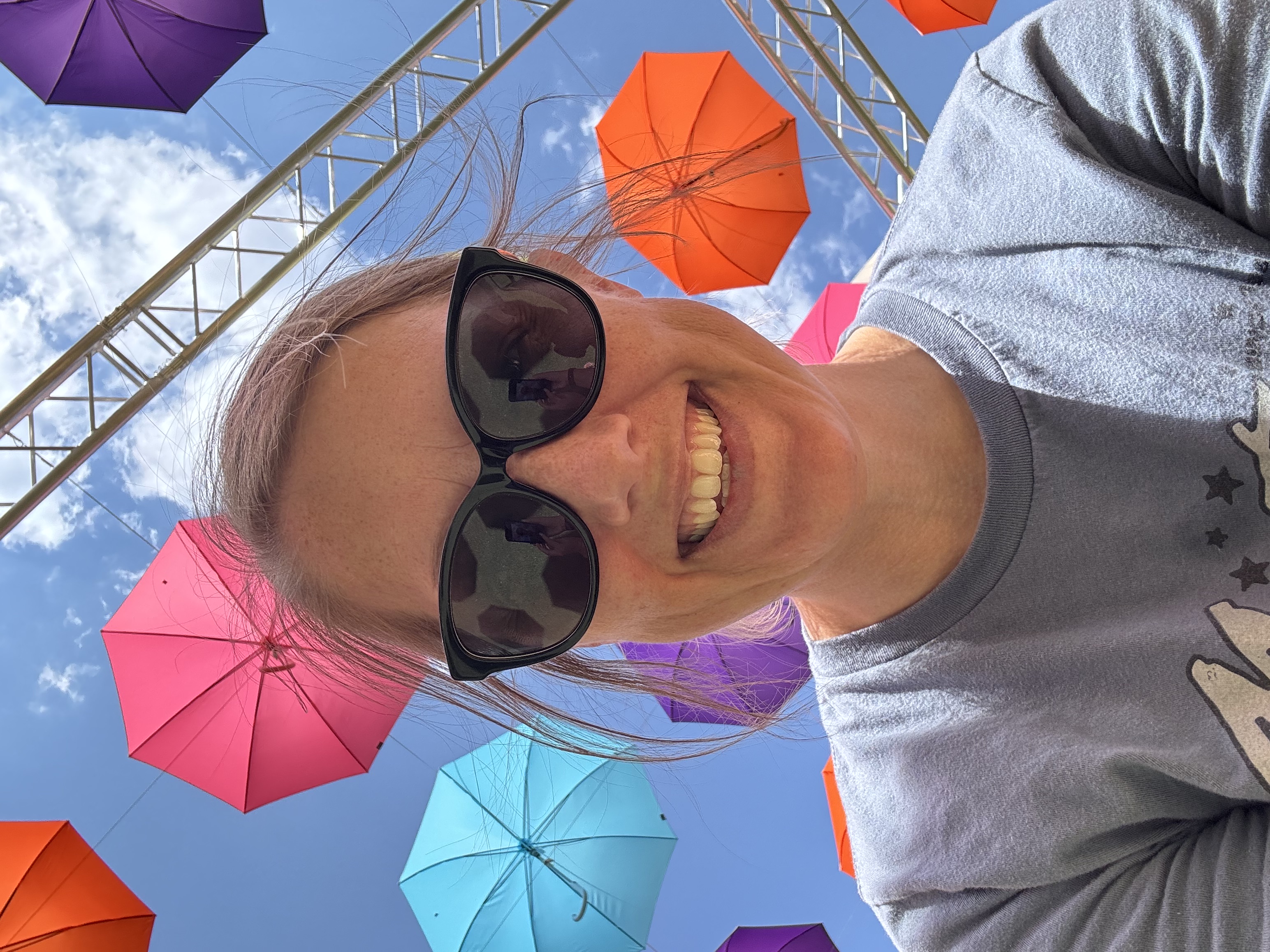 Sarah, creator of Bright Spark Design, smiling beneath colorful umbrellas